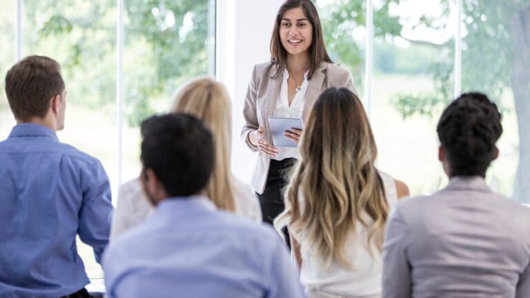 Person leading a business seminar with a group of listeners.