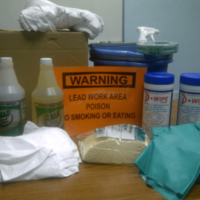 Lead safety cleaning supplies and warning sign on table.