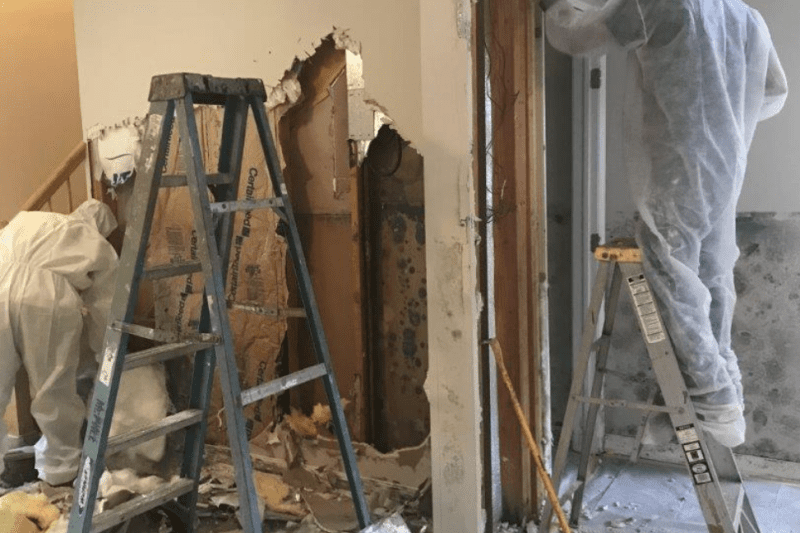 Home renovation with workers removing drywall.