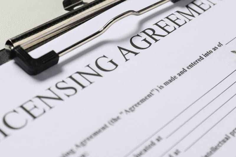 Licensing agreement document on clipboard with pen.