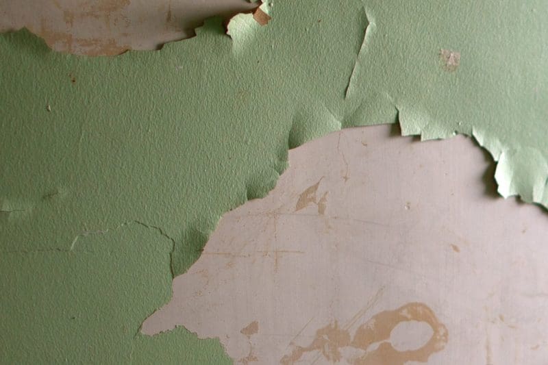 Peeling green paint on an old wall surface.