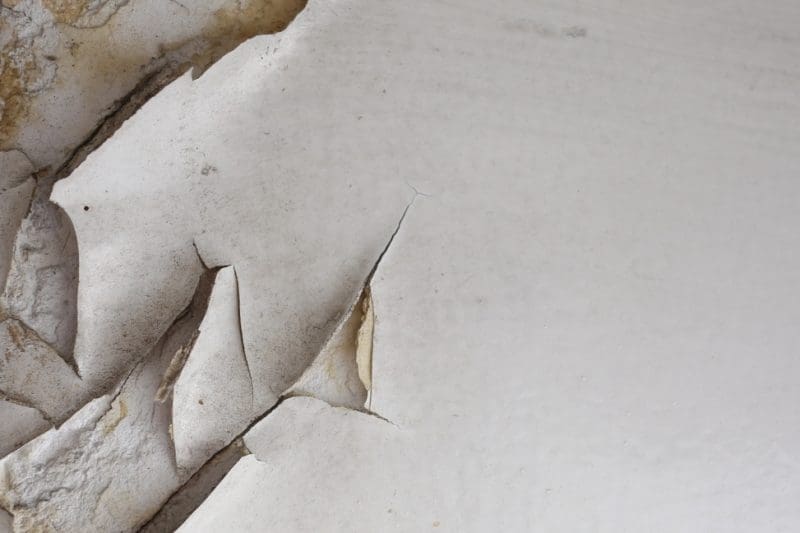 Peeling paint on an old, cracked wall surface.