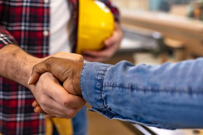 Two people shaking hands in a construction setting.
