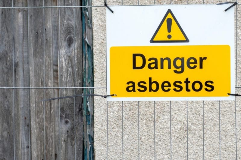 Warning sign for asbestos danger on a wire fence.