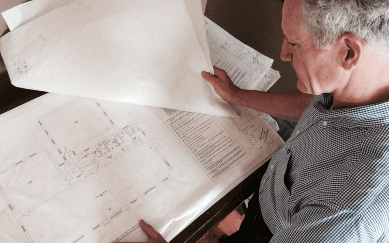 Architect reviewing building blueprints on a table.