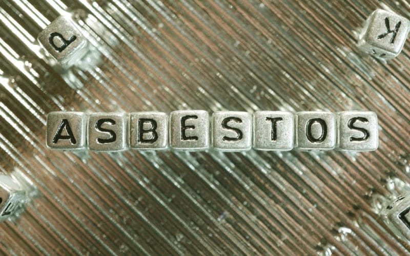 Asbestos spelled with letter cubes on metallic background.