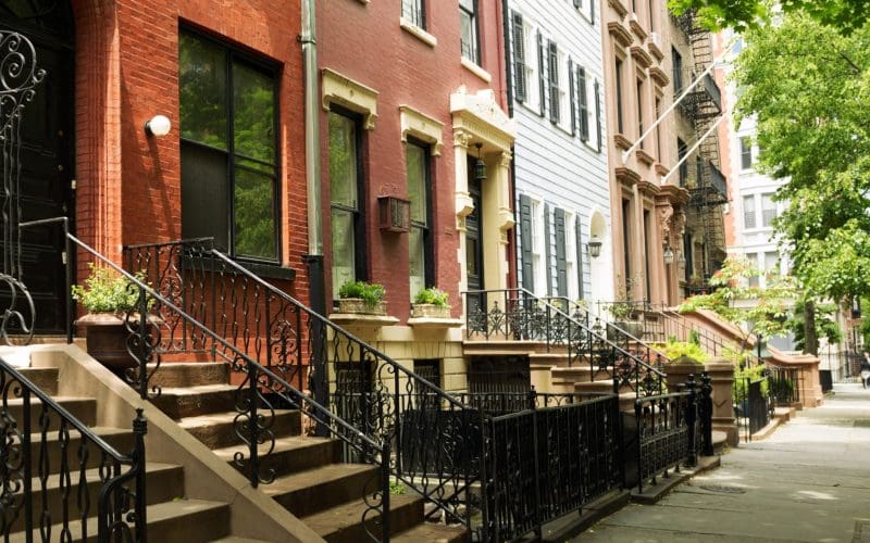 Brownstone homes on a tree-lined urban street.