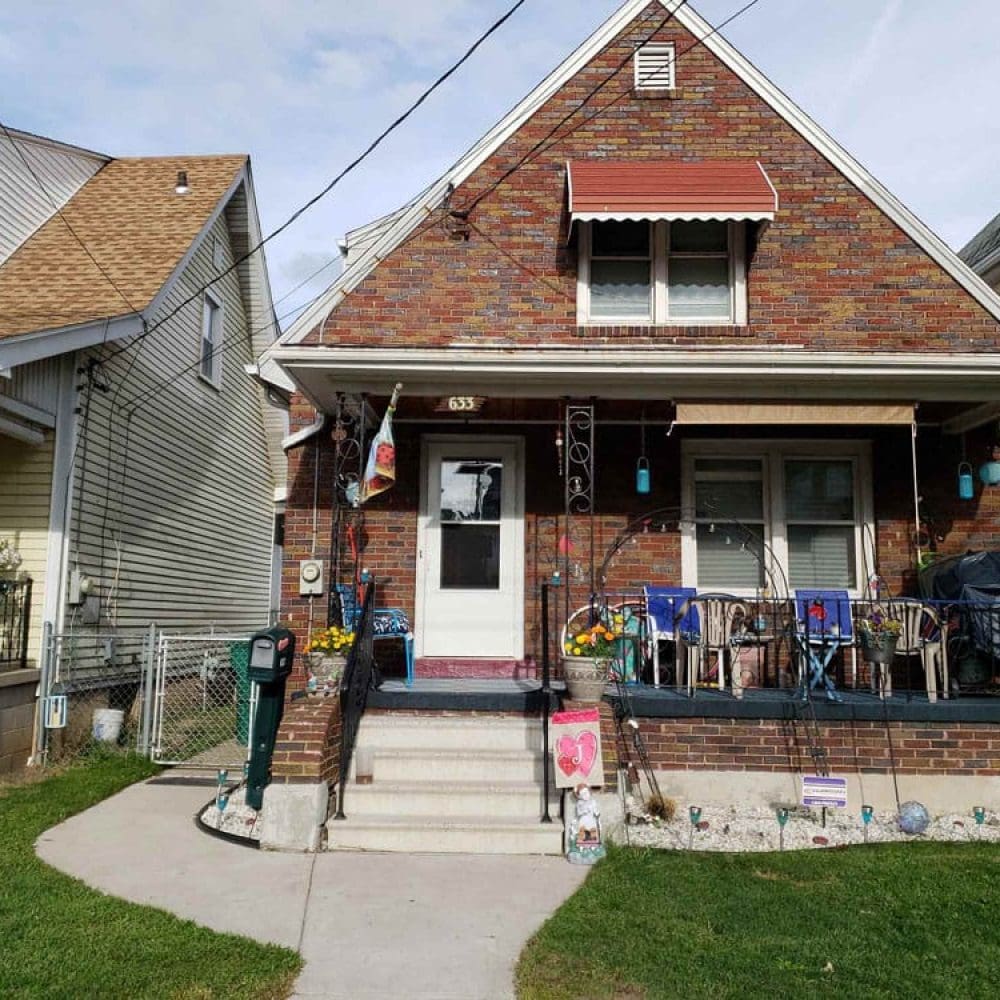 Brick house with porch, decorated seating area, and garden ornaments.