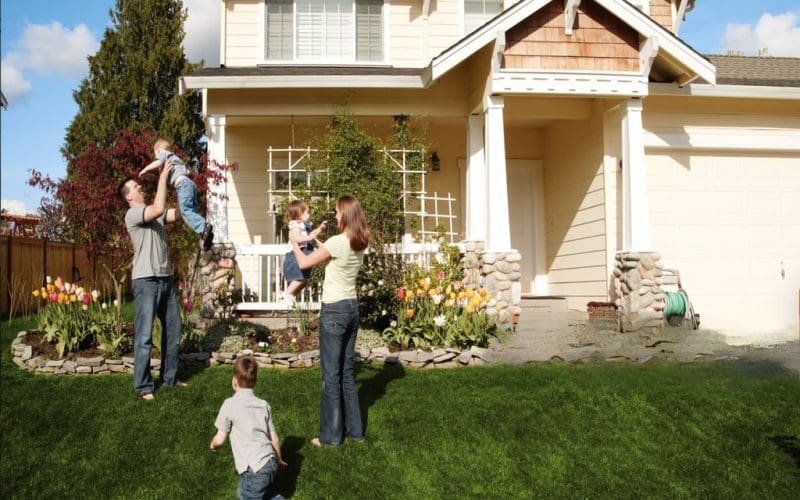 Family playing together in front yard of suburban home.