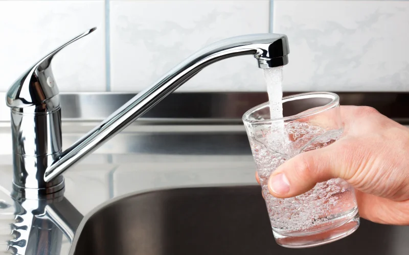 Filling a glass with water from a kitchen faucet.