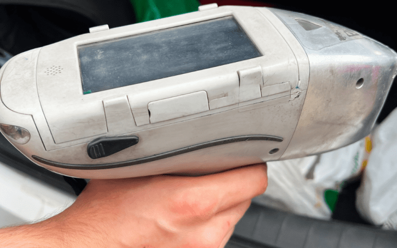 Hand holding a handheld scanner device in a vehicle.