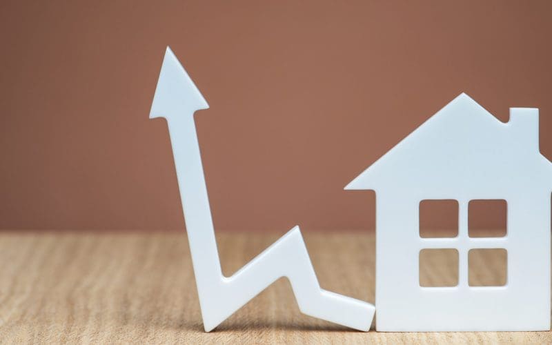 Housing market growth concept with arrow chart and small house model.
