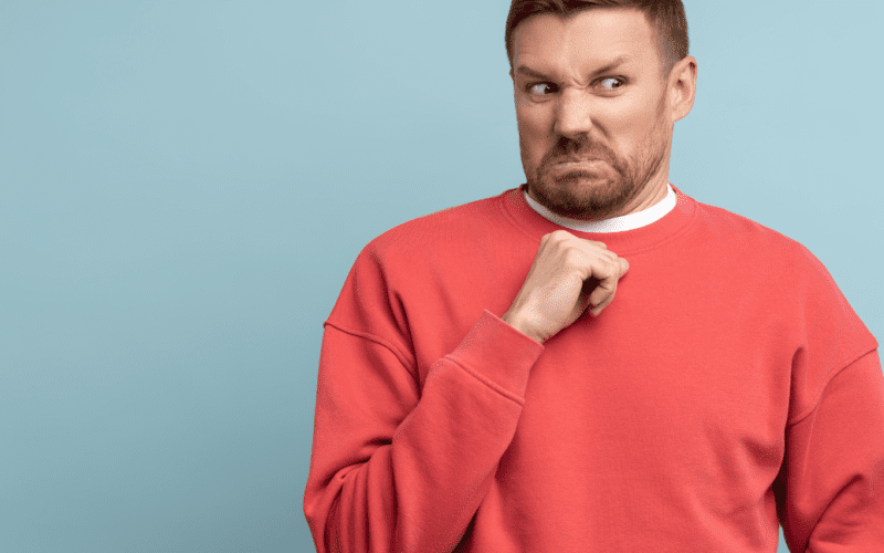 Man in red sweater making a disgusted facial expression.