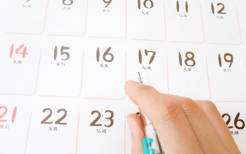 Marking a date on a white calendar with a pen.