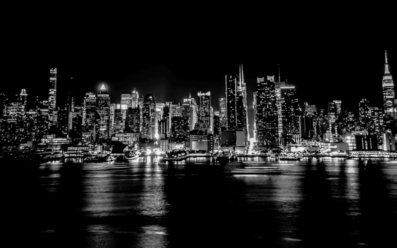 New York City skyline at night with reflections on water.