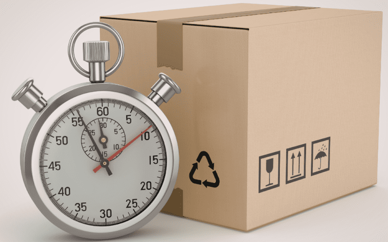 Stopwatch next to a cardboard box, symbolizing speedy delivery.