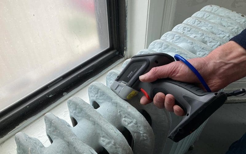 Thermal camera checking radiator temperature near window.