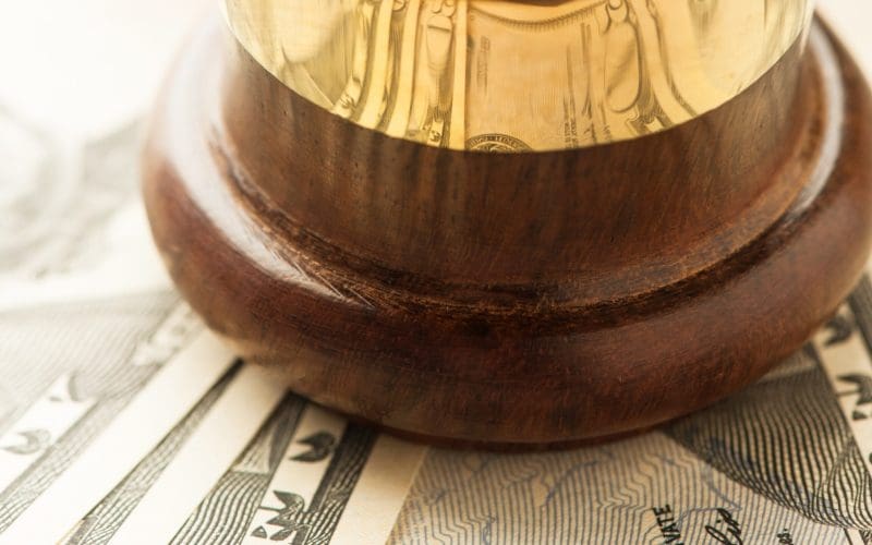 Wooden gavel rests atop a spread of dollar bills.