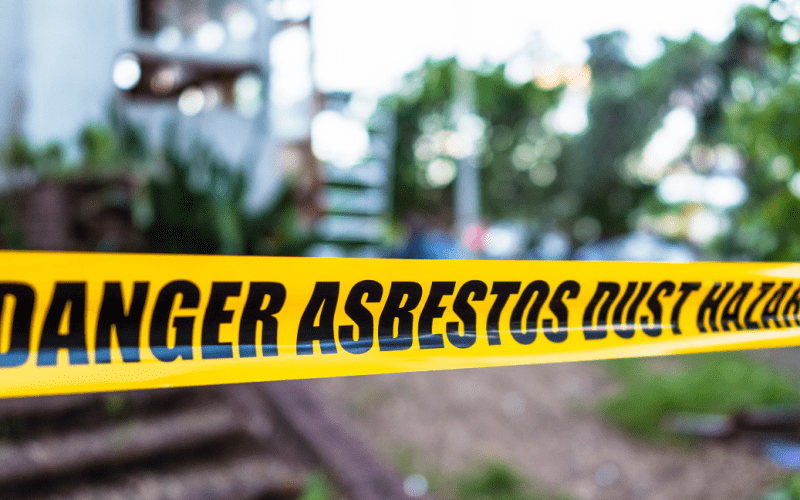 Yellow tape warning about asbestos dust hazard in construction area.