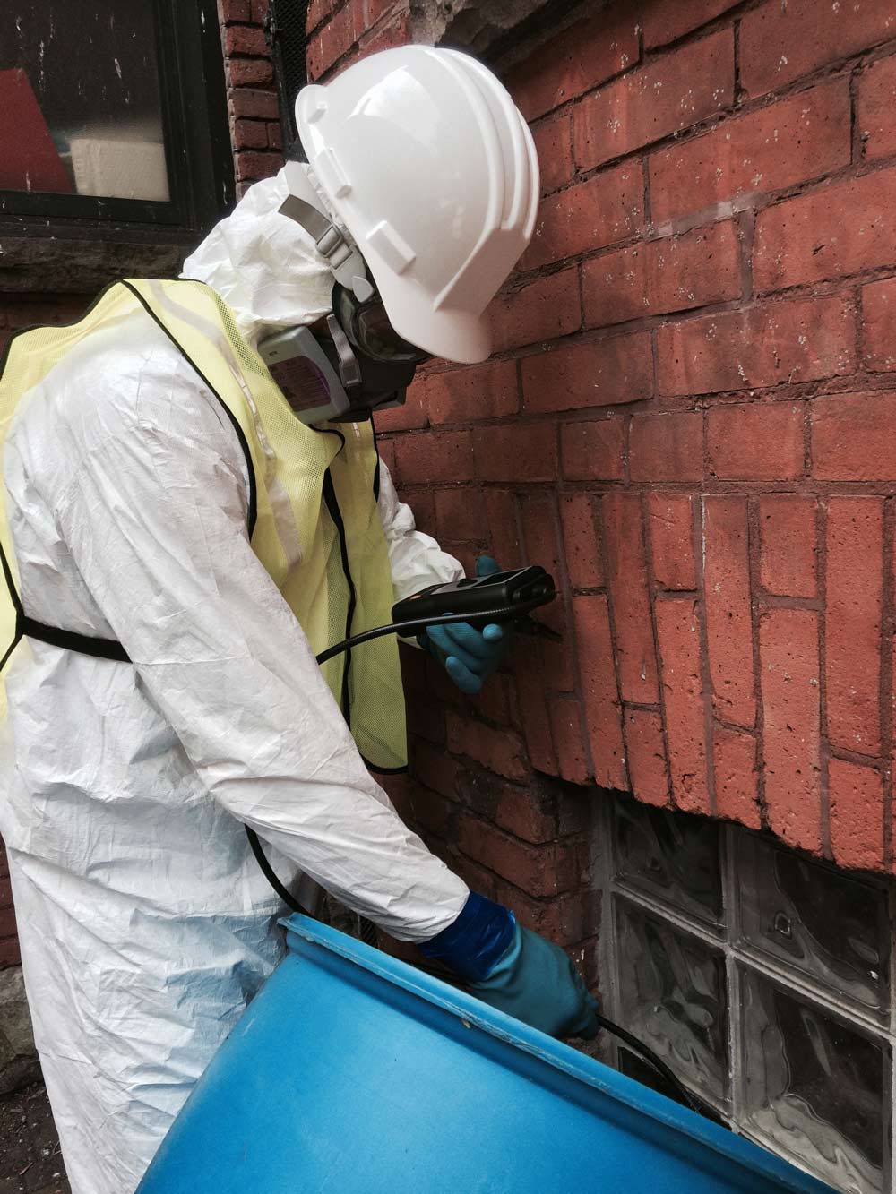 Worker in protective gear inspecting building foundation.