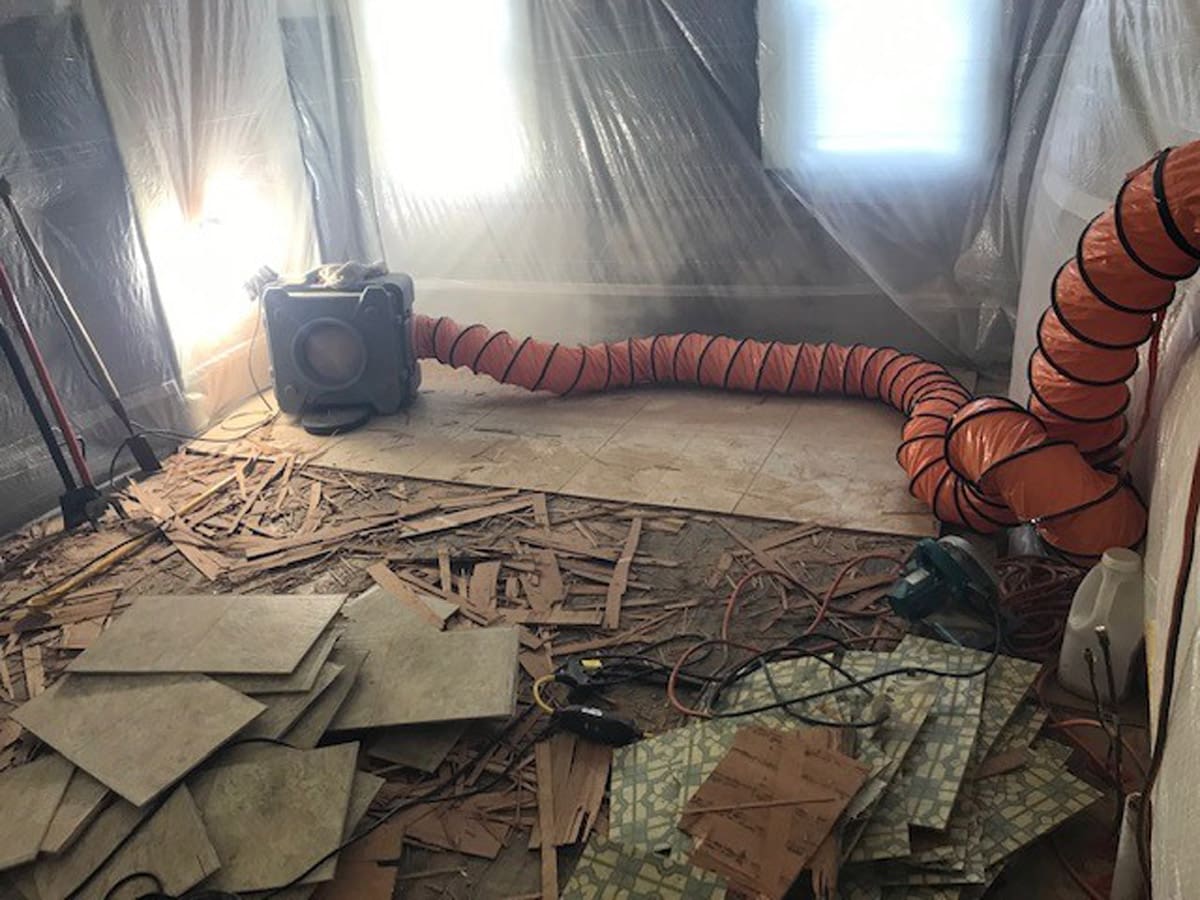 Room during flooring renovation with debris and ventilation system.