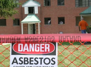 Danger asbestos sign in front of a fenced-off building.
