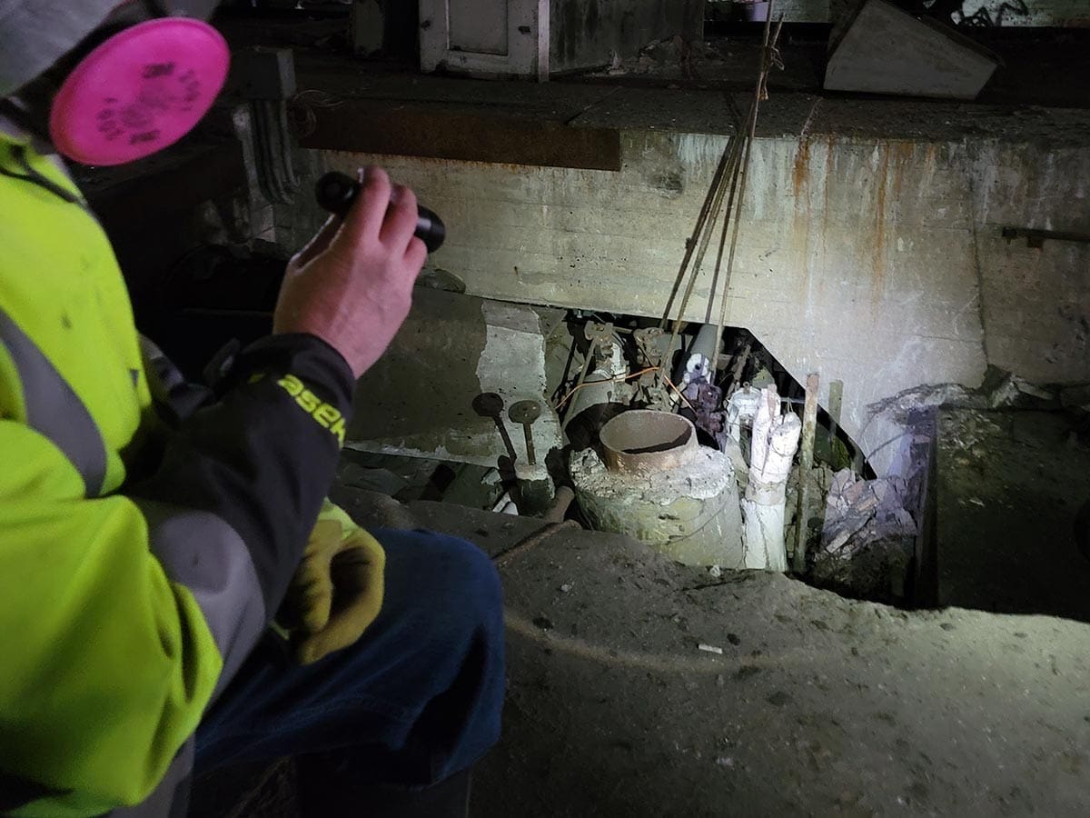 Worker inspects industrial equipment in a dimly lit area.