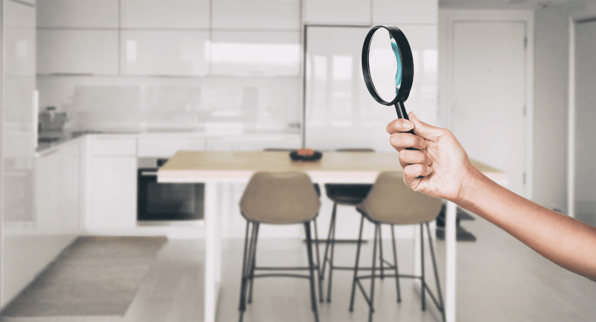 Hand holding magnifying glass in modern kitchen.