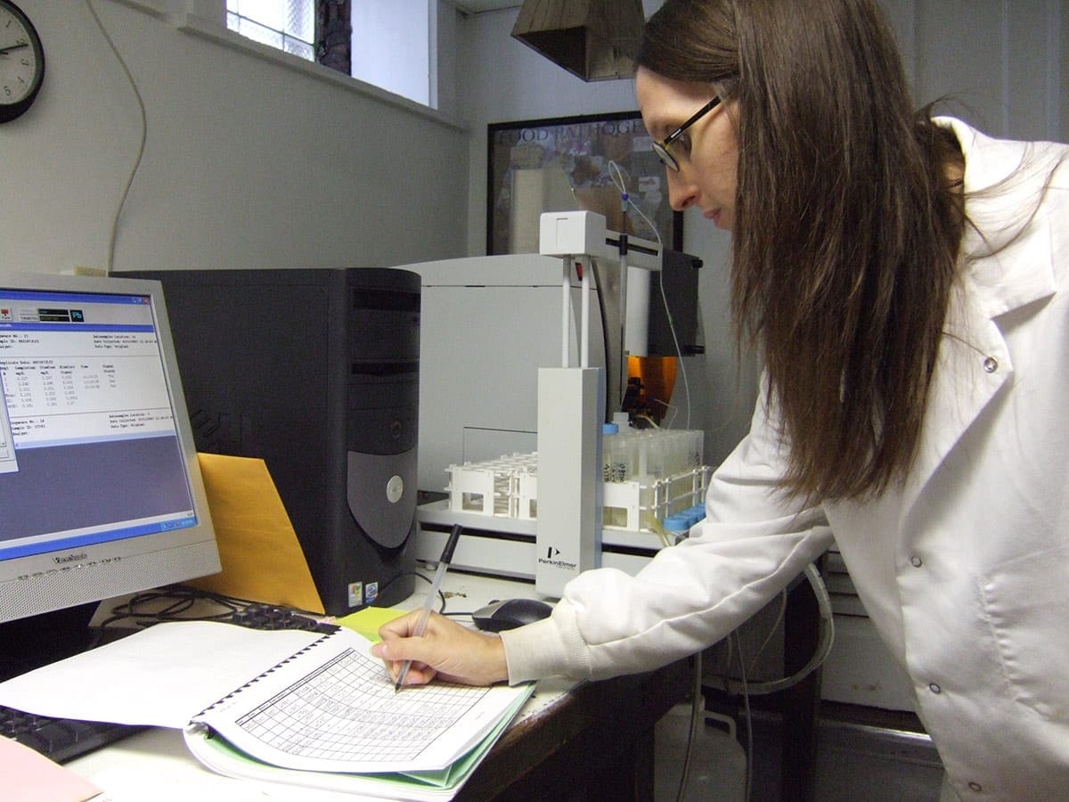 Technician recording lab results on computer.
